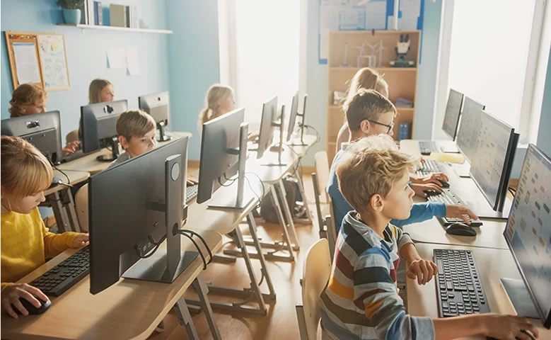 Classroom of children sitting behind computers and typing.