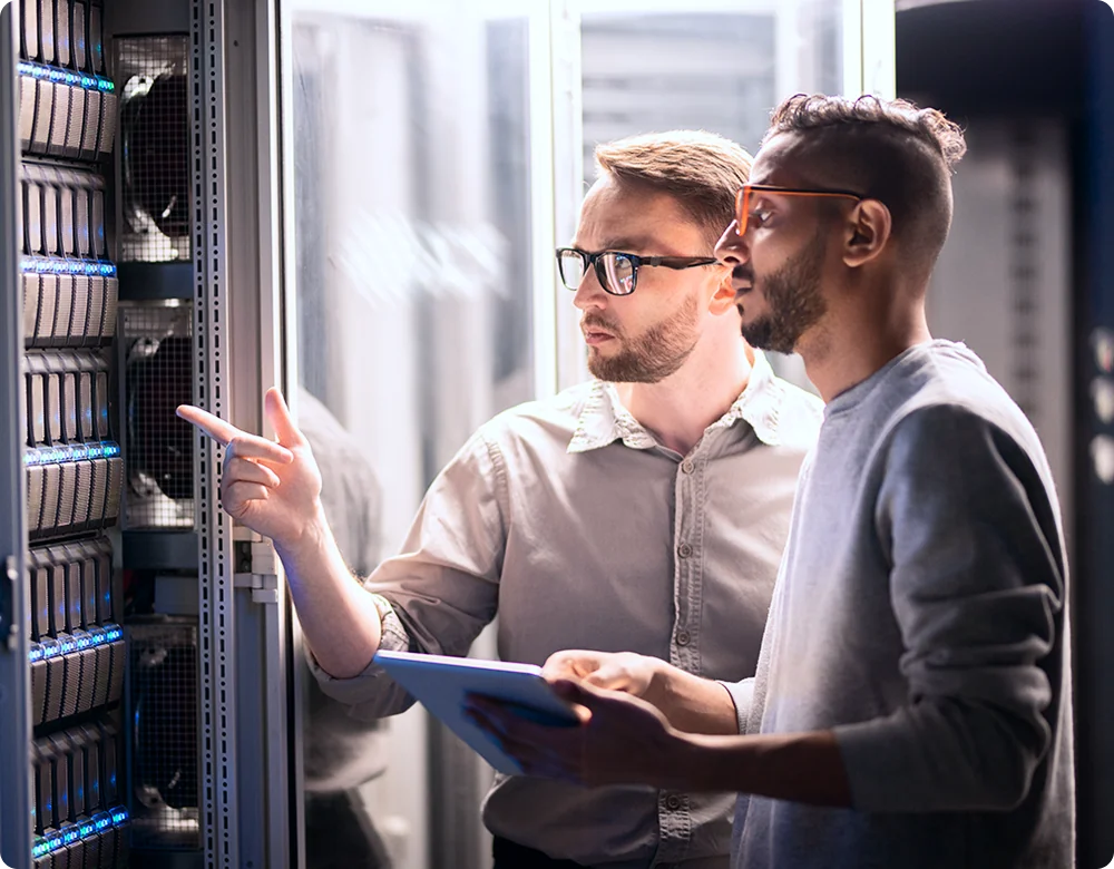 Datacenter 2 Two men in glasses provide IT support inside of a server room.